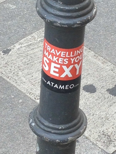 Street light with sticker that says: Traveling makes you sexy