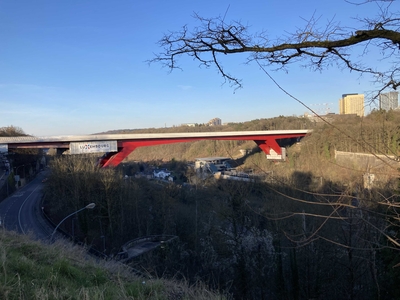 A modern red bridge connecting the two bluffs separated by the river