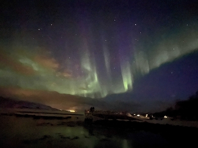 Kate and Maggie on a dock gazing at the stunning green and purple northern lights